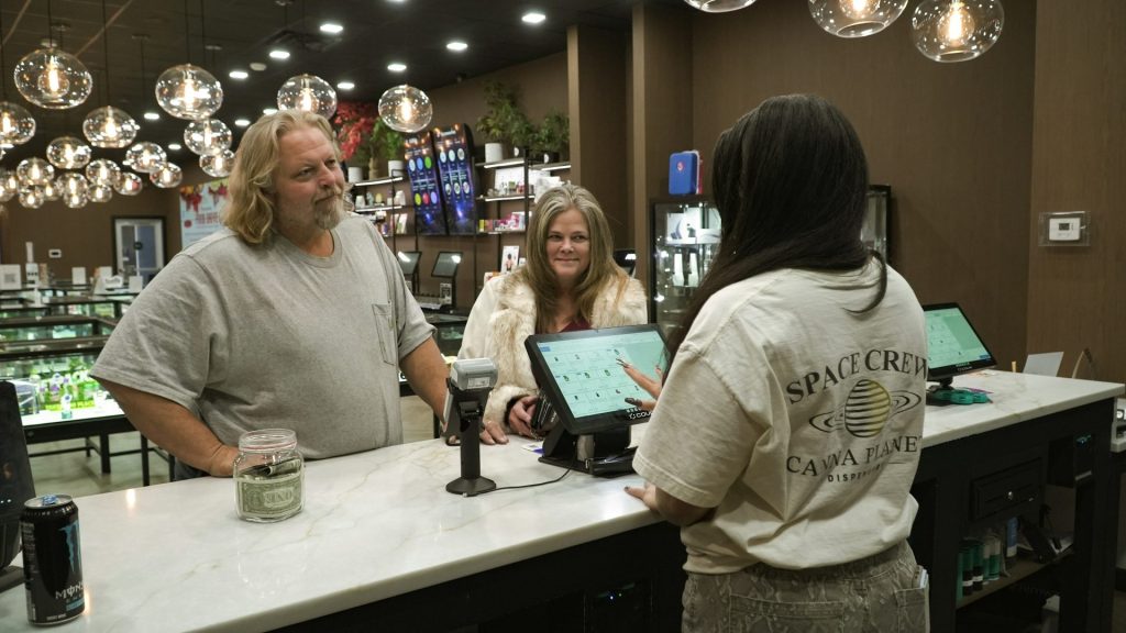 Customers interact with staff at a dispensary counter.